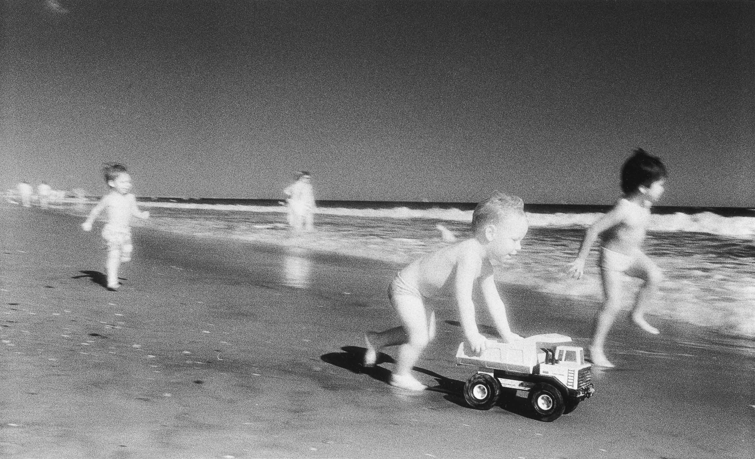 Barbara Alper- Photo of young boys playing with a toy truck on Rockaway Beach NYC