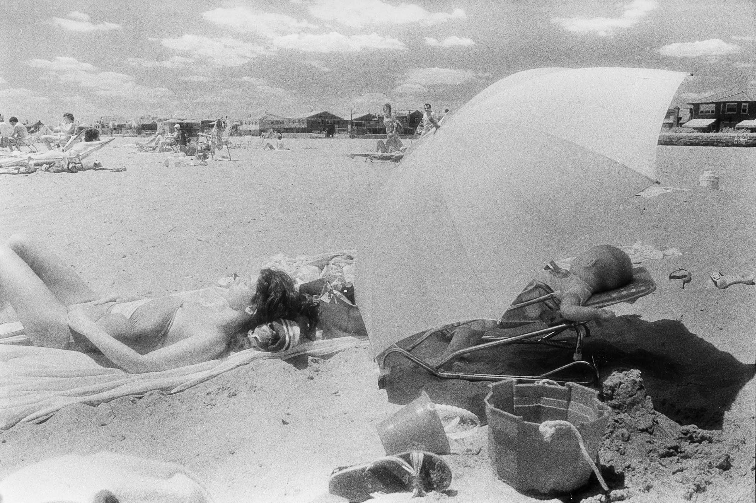 Barbara Alper- Photo of women and baby sleeping under umbrella at Rockaway Beach NYC