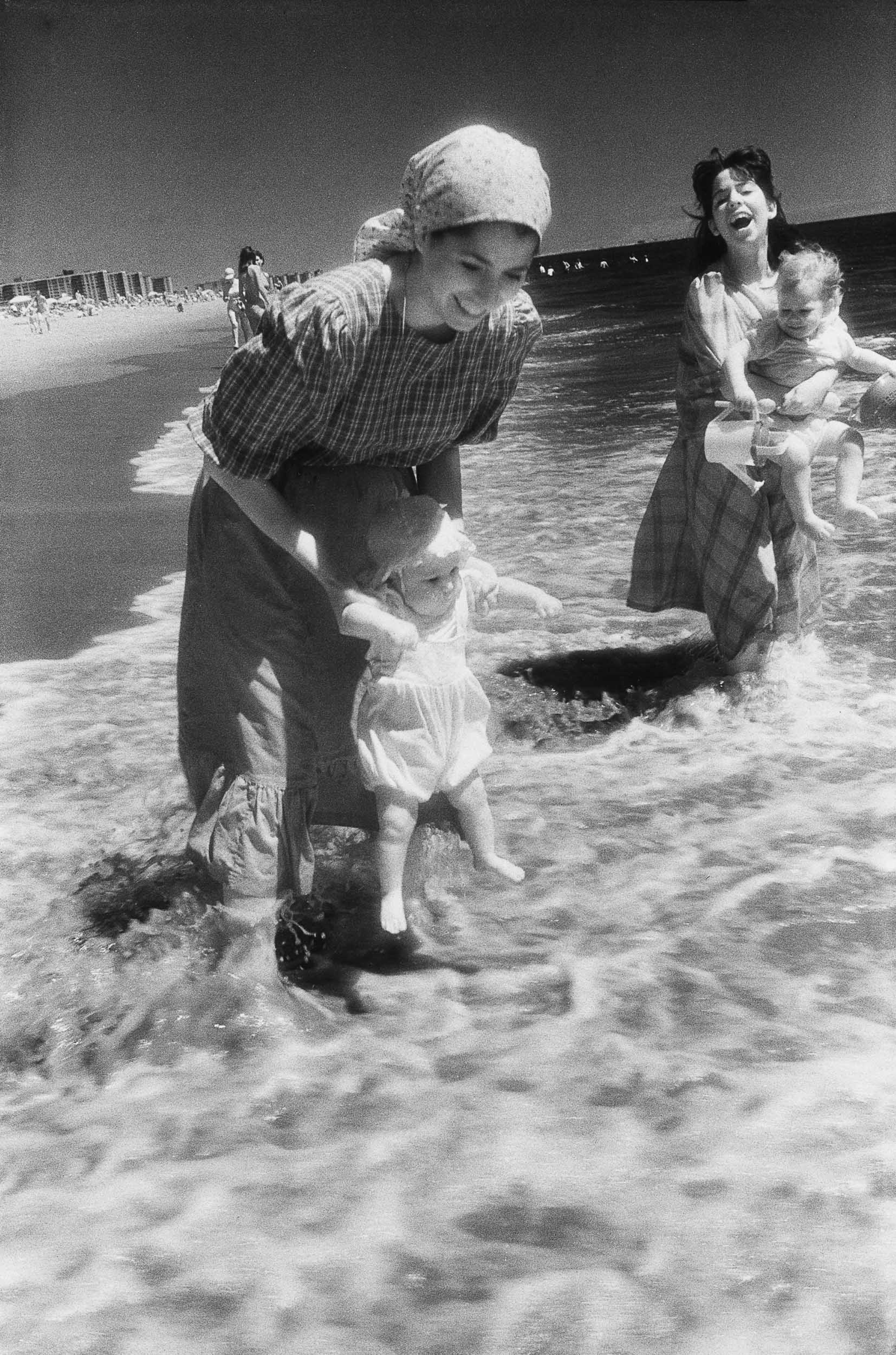 Barbara Alper- Photo of orthodox women holding babies in the water at Rockaway Beach NYC
