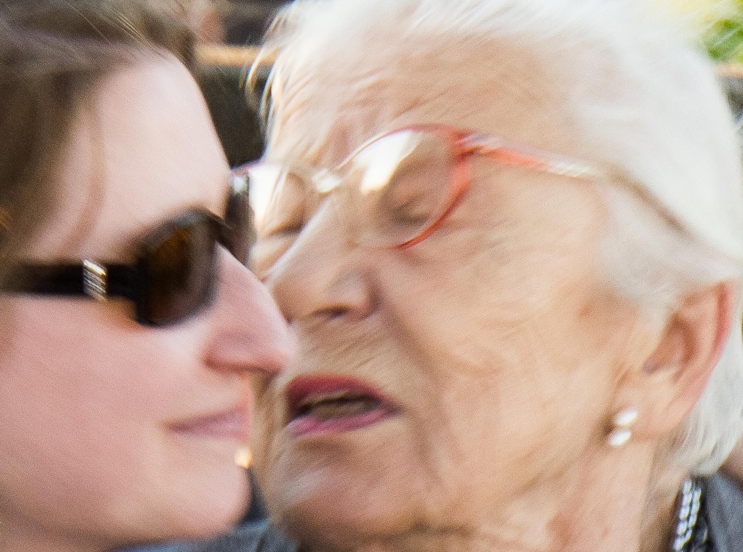Barbara Alper- Photo of two women greeting, one younger and one elder, faces  together, emotional, in motion, closeup