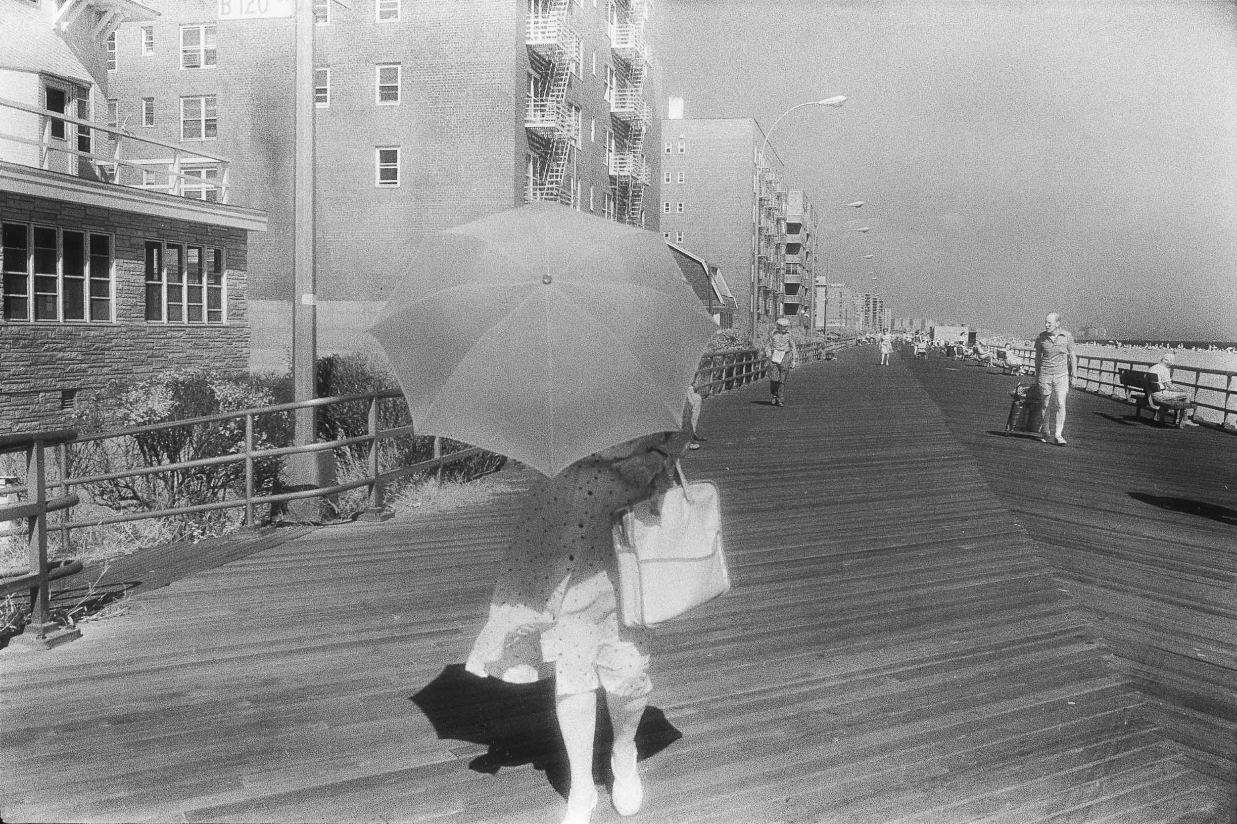 Barbara Alper- Photo of woman with umbrella on the  Boardwalk at Rockaway Beach NYC